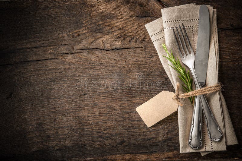 Vintage silverware with a twig of rosemary and empty tag on rustic wooden background. Vintage silverware with a twig of rosemary and empty tag on rustic wooden background