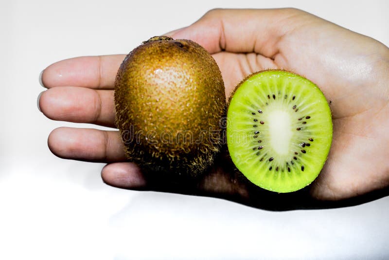 Argomento sano di dieta e di cibo: Mano umana che giudica un mezzo kiwi isolato su un fondo bianco nello studio fotografia stock