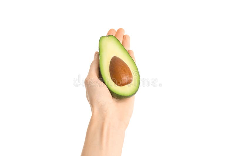 Argomento sano di dieta e di cibo: Mano umana che giudica un mezzo avocado isolato su un fondo bianco nello studio, vista in prim fotografie stock