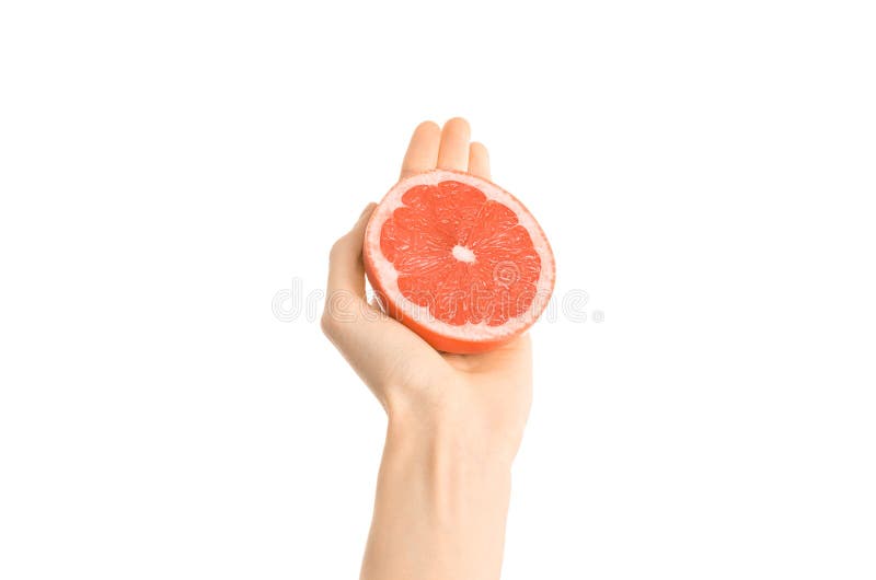Argomento sano di dieta e di cibo: Mano umana che giudica una metà del pompelmo isolata su un fondo bianco nello studio, in prima immagine stock
