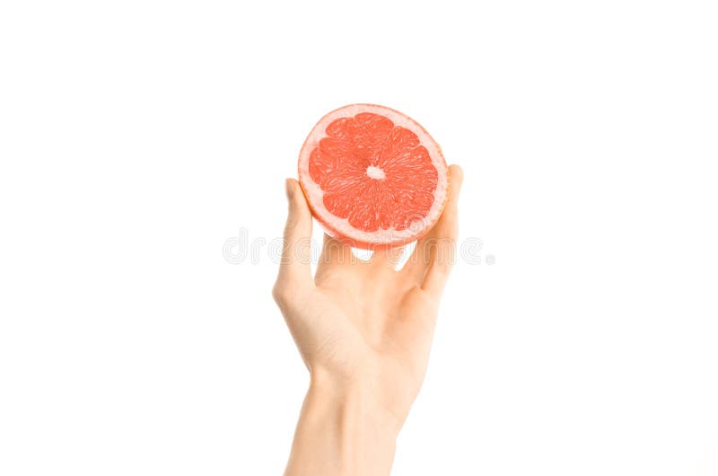 Argomento sano di dieta e di cibo: Mano umana che giudica una metà del pompelmo isolata su un fondo bianco nello studio, in prima fotografie stock