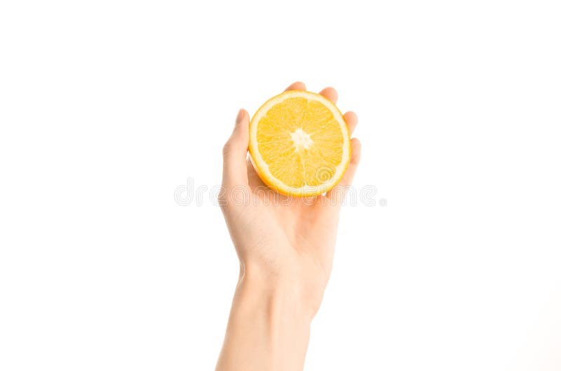 Argomento sano di dieta e di cibo: Mano umana che giudica una metà dell'arancia isolata su un fondo bianco nello studio, vista in fotografia stock libera da diritti
