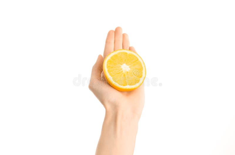 Argomento sano di dieta e di cibo: Mano umana che giudica una metà dell'arancia isolata su un fondo bianco nello studio, vista in fotografia stock