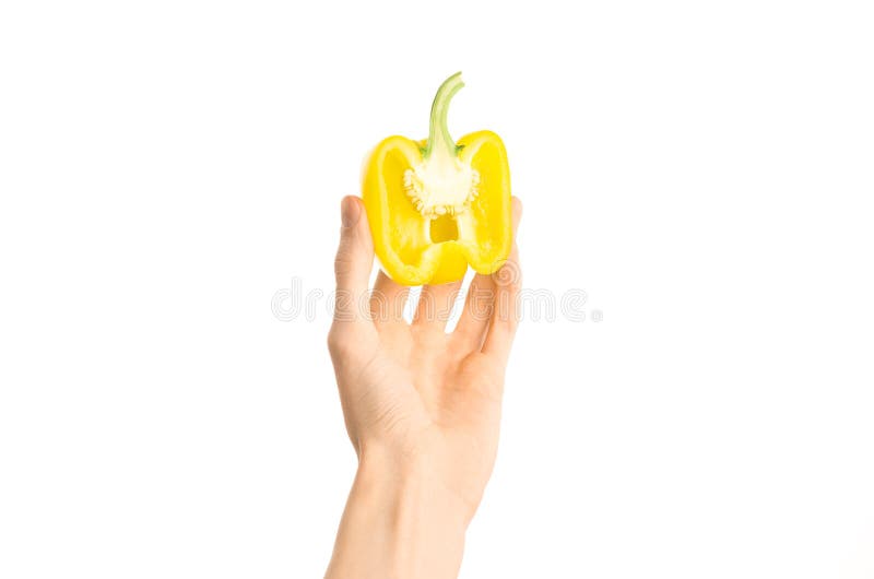 Argomento sano di dieta e di cibo: Mano umana che giudica una metà di pepe giallo isolata su un fondo bianco nello studio, primo- immagini stock