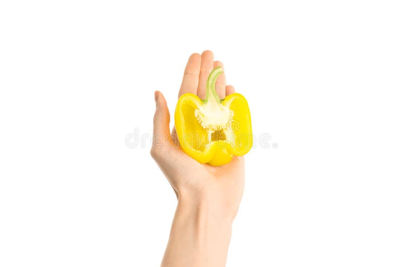 Argomento sano di dieta e di cibo: Mano umana che giudica una metà di pepe giallo isolata su un fondo bianco nello studio, primo- fotografia stock libera da diritti