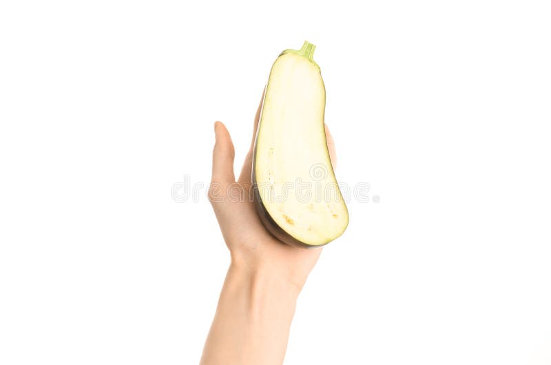 Argomento sano di dieta e di cibo: Mano umana che giudica una mezza melanzana isolata su un fondo bianco nello studio, vista in p fotografia stock