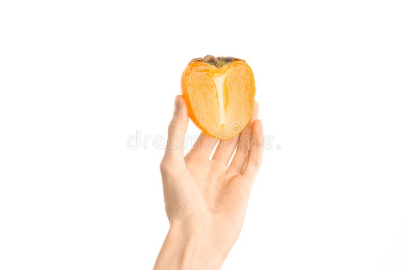 Argomento sano di dieta e di cibo: Mano umana che tiene una metà dei cachi isolati su fondo bianco nello studio, vi in prima pers fotografia stock libera da diritti