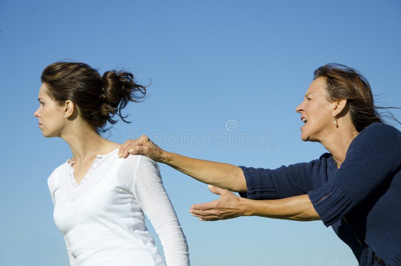 Argument between mother and daughter. Daughter is trying to get away while mother desperately is holding her back. Clear blue sky as background and copy space. Argument between mother and daughter. Daughter is trying to get away while mother desperately is holding her back. Clear blue sky as background and copy space.