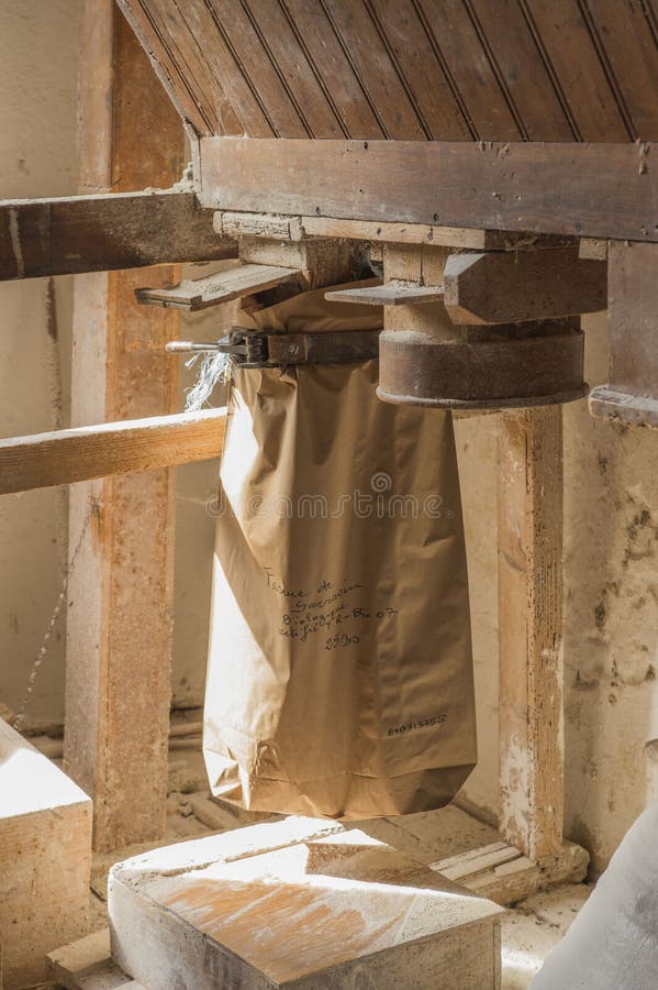 Ariege, France, 2015. Traditional wooden flour mill equipment, feeding freshly milled flour into paper flour bags