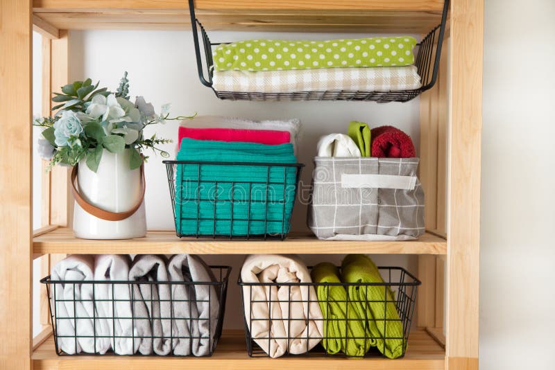 Spring cleaning of closet. Vertical tidying up storage. Neatly folded bed sheets in the metal black baskets for wardrobe. Nordic style. Spring cleaning of closet. Vertical tidying up storage. Neatly folded bed sheets in the metal black baskets for wardrobe. Nordic style