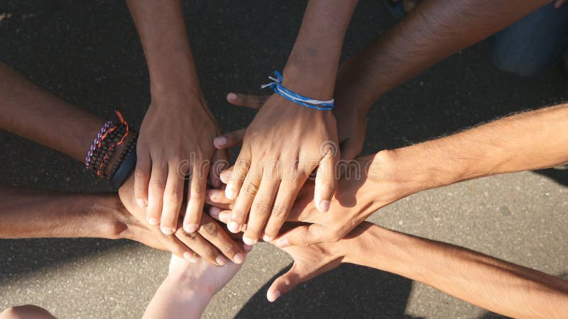 Arm of all races and colors stacked together one by one in unity and teamwork and then raised. Many multiracial hands