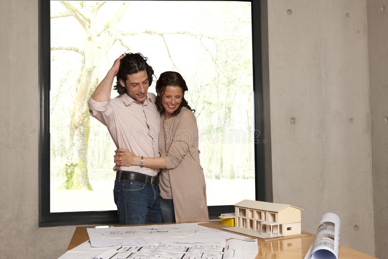 Young man showing his wife the plans for their new home. Young man showing his wife the plans for their new home