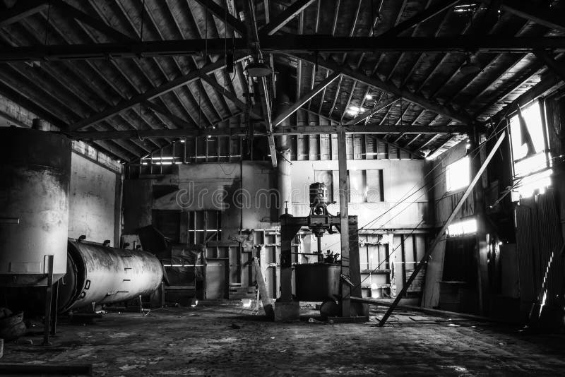 Black and white dramatic interior abandoned cannery warehouse building.  Old equipment and crumbling walls in rustic grungy historic building. Black and white dramatic interior abandoned cannery warehouse building.  Old equipment and crumbling walls in rustic grungy historic building