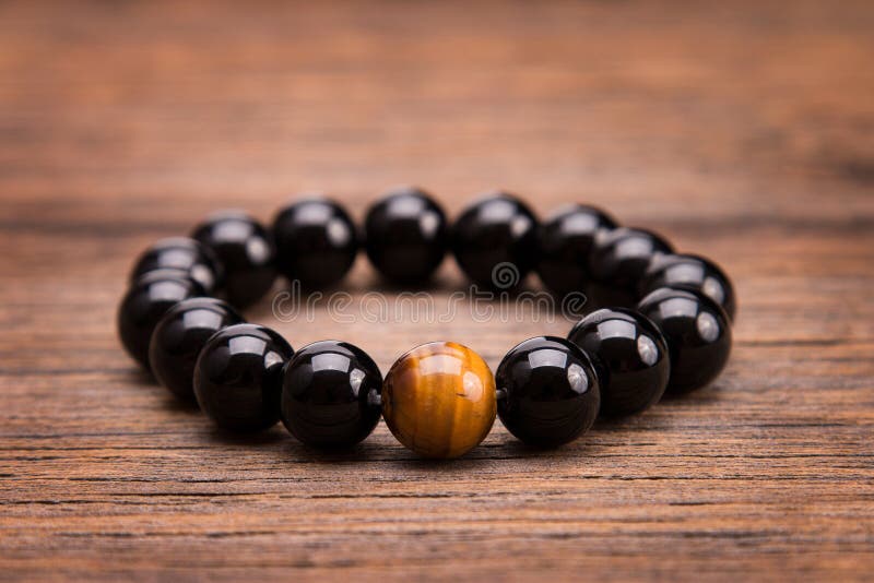 Armband von den runden schwarzen Steinen, die auf einem hölzernen Hintergrund liegen stockfotos Armband von den runden schwarzen Steinen, die auf einem hölzernen Hintergrund liegen stockfotos