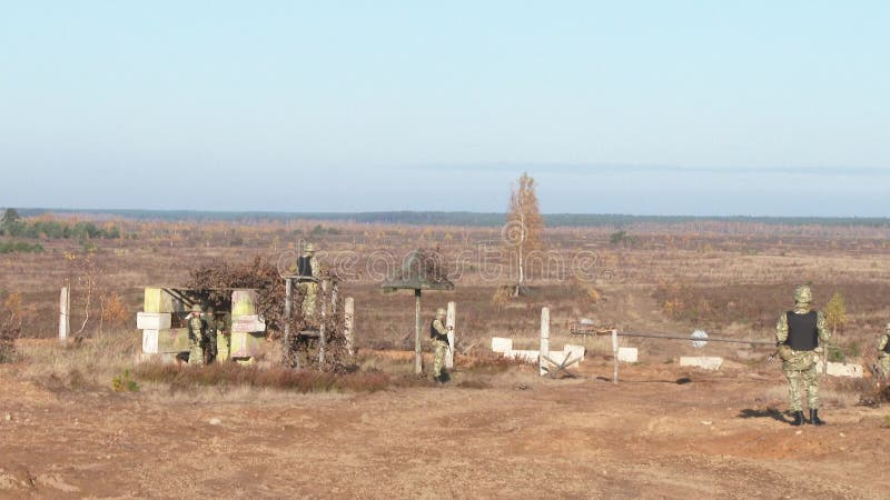 Armed soldiers patrol the territory. A column of vehicles is approaching a protected area.