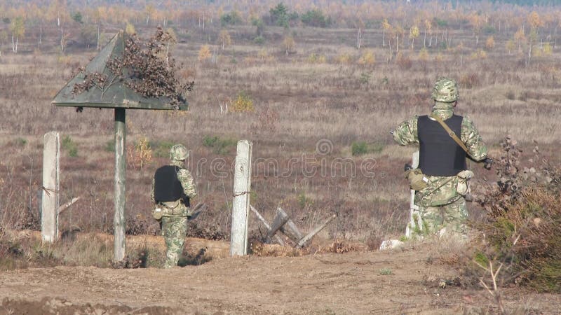 Armed soldiers patrol the territory. A column of vehicles is approaching a protected area.