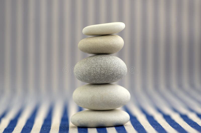 Armonía y balanza, mojón de la roca del guijarro, piedras simples del equilibrio en el fondo rayado blanco y azul, escultura del fotos de archivo libres de regalías Armonía y balanza, mojón de la roca del guijarro, piedras simples del equilibrio en el fondo rayado blanco y azul, escultura del fotos de archivo libres de regalías