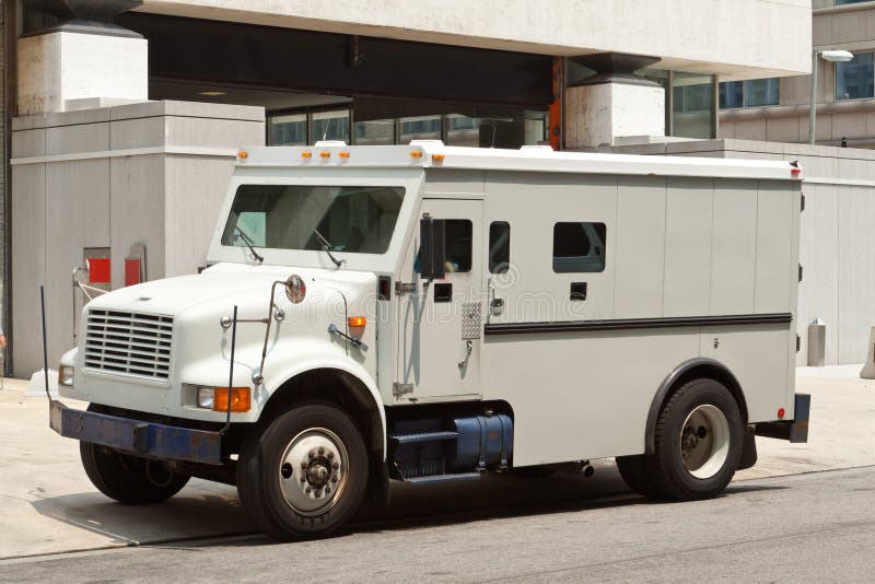 Side view of gray armored truck parked on street making a cash pickup. Side view of gray armored truck parked on street making a cash pickup.