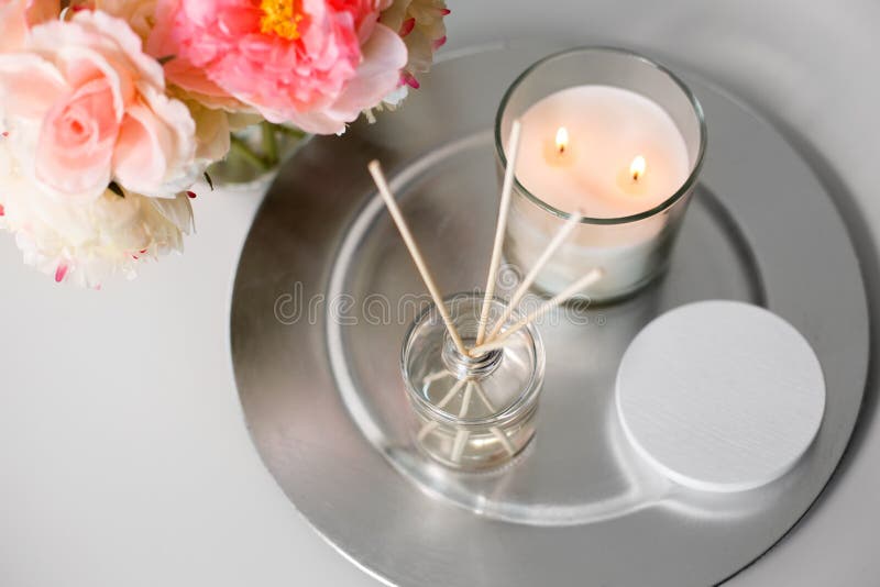Aroma reed diffuser, świeca i kwiaty na stole