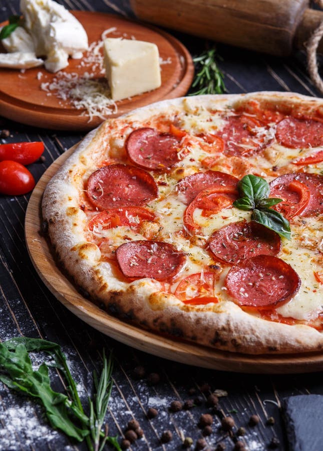 Aromatic pizza with sausage and tomatoes is decorated with basil