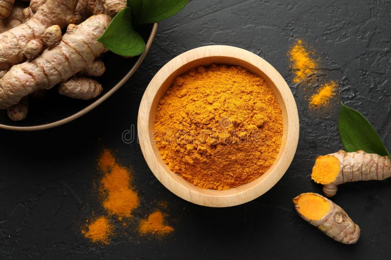 Aromatic turmeric powder in bowl fresh roots and leaves on black table flat lay royalty-vrije stock foto