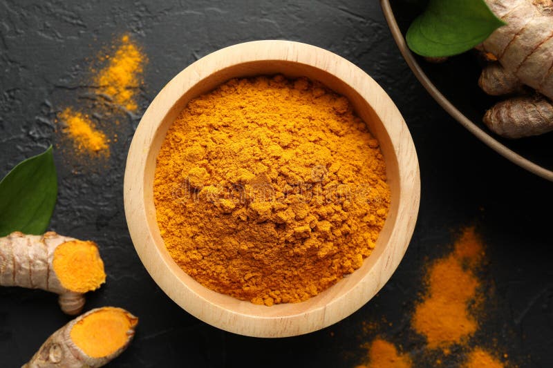 Aromatic turmeric powder in bowl fresh roots and leaves on black table flat lay royalty-vrije stock afbeelding