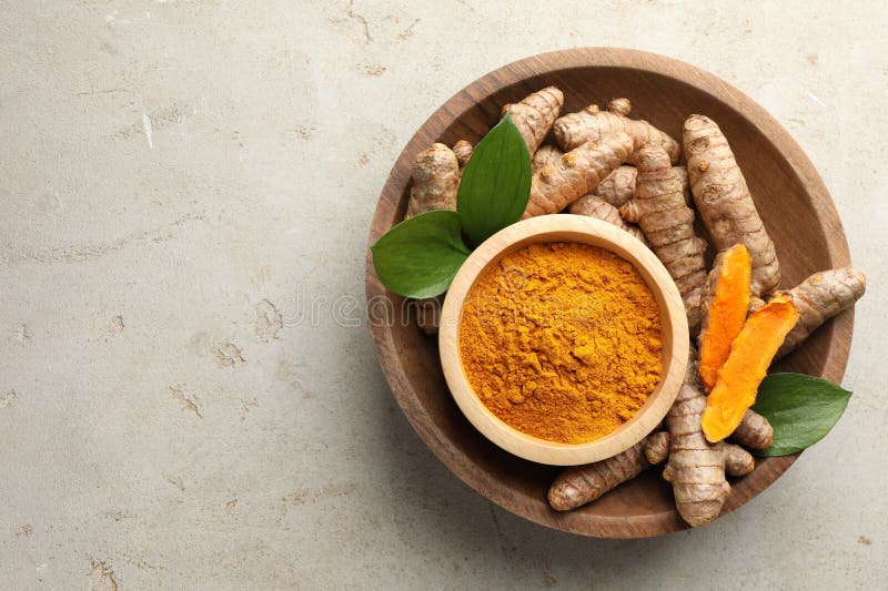 Aromatic turmeric powder in bowl fresh roots and leaves on light grey table top view space for text stock fotografie
