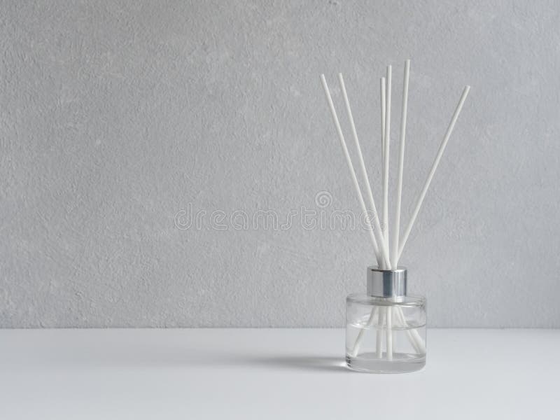 Aromatizer. Aromatic air freshener in a transparent glass bottle with white reeds on a gray background royalty free stock photo Aromatizer. Aromatic air freshener in a transparent glass bottle with white reeds on a gray background royalty free stock photo