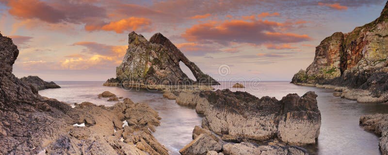Arquee a Fiddle Rock en la costa del Moray, Escocia en la puesta del sol