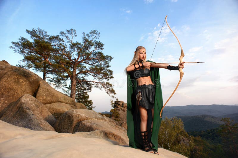 Arquero de sexo femenino hermoso del duende en la caza del bosque con un arco imágenes de archivo libres de regalías Arquero de sexo femenino hermoso del duende en la caza del bosque con un arco imágenes de archivo libres de regalías