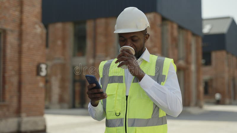Arquitecto tomando café y usando el móvil en el lugar de construcción almacen de metraje de vídeo
