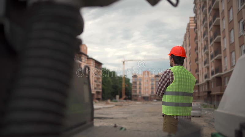 Arquitectura temática e ingeniería civil. joven inspector masculino en el lugar de construcción, de vuelta a la cámara y