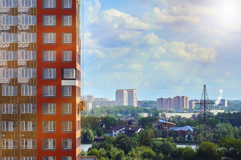 A arquitetura da cidade de Moscou com um trabalhador em um berço da construção na parede de uma construção sob a construção ilumi fotografia de stock royalty free A arquitetura da cidade de Moscou com um trabalhador em um berço da construção na parede de uma construção sob a construção ilumi fotografia de stock royalty free