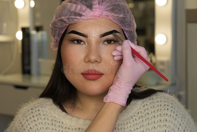 Microbleeding and eyebrow architecture. Beautician applies coloring pigment to girl`s brow. Cosmetic procedure in spa salon. Microbleeding and eyebrow architecture. Beautician applies coloring pigment to girl`s brow. Cosmetic procedure in spa salon