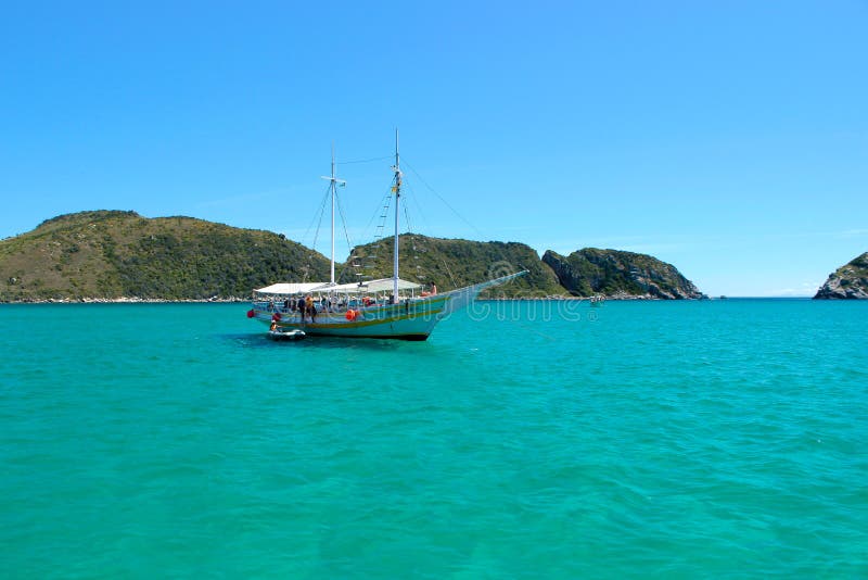 ARRAIAL FONT CABO, RIO DE JANEIRO, BRÉSIL 21 MARS 2016 : Voilier et un bateau au-dessus des eaux vertes et claires près d'une côt images libres de droits ARRAIAL FONT CABO, RIO DE JANEIRO, BRÉSIL 21 MARS 2016 : Voilier et un bateau au-dessus des eaux vertes et claires près d'une côt images libres de droits