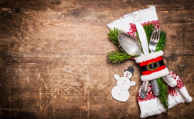 Arrangement de table de Noël avec le décor, la serviette, les couverts et le bonhomme de neige de fête sur le fond en bois rustiq image libre de droits Arrangement de table de Noël avec le décor, la serviette, les couverts et le bonhomme de neige de fête sur le fond en bois rustiq image libre de droits