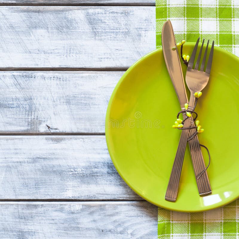 Spring table setting with green plate over wooden table background. View from above with copy space. Spring table setting with green plate over wooden table background. View from above with copy space