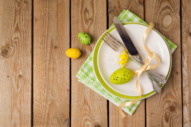 Easter holiday table setting with plate and eggs decoration on wooden background. Top view from above. Easter holiday table setting with plate and eggs decoration on wooden background. Top view from above