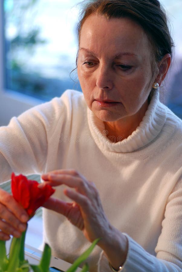 Una donna più grande organizzazione di alcuni fiori rossi.