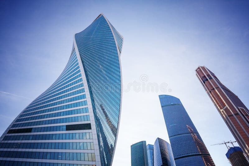Arranha-céus de vidro modernos contra o céu azul e as nuvens, a construção do centro de negócios em Moscou imagem de stock royalty free Arranha-céus de vidro modernos contra o céu azul e as nuvens, a construção do centro de negócios em Moscou imagem de stock royalty free