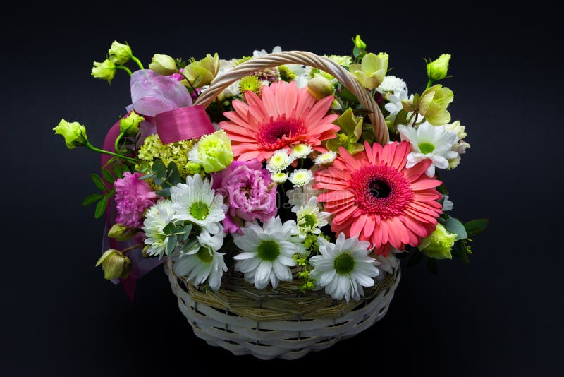 Arranjo de flor brilhante em uma cesta branca em flores escuras de um fundo em uma cesta de vime fotografia de stock Arranjo de flor brilhante em uma cesta branca em flores escuras de um fundo em uma cesta de vime fotografia de stock