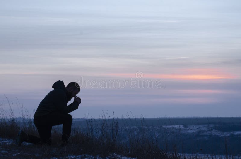 Arrepentimiento. un hombre de rodillas. oración. silueta de un hombre sobre un fondo azul del cielo. rezando arrodillando a dios.