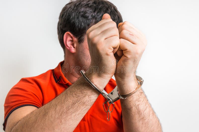Arrested man in handcuffs hidden his face