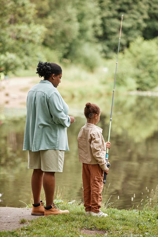 Arrière vue mère et fille pêche ensemble par rivière et profiter de la nature photographie stock