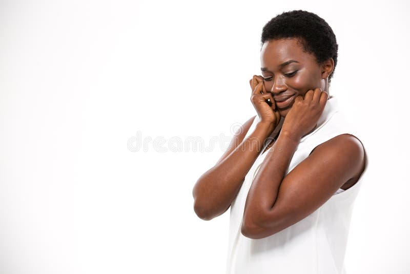 Shy cute african american young woman standing and touching her cheeks over white background. Shy cute african american young woman standing and touching her cheeks over white background