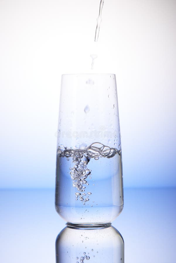 Arrosez le versement dans le verre à boire à moitié plein image stock Arrosez le versement dans le verre à boire à moitié plein image stock