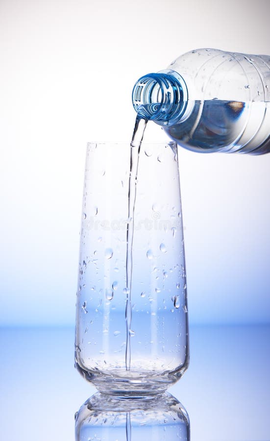 Arrosez le versement de la bouteille en plastique dans le verre à boire vide photos libres de droits Arrosez le versement de la bouteille en plastique dans le verre à boire vide photos libres de droits