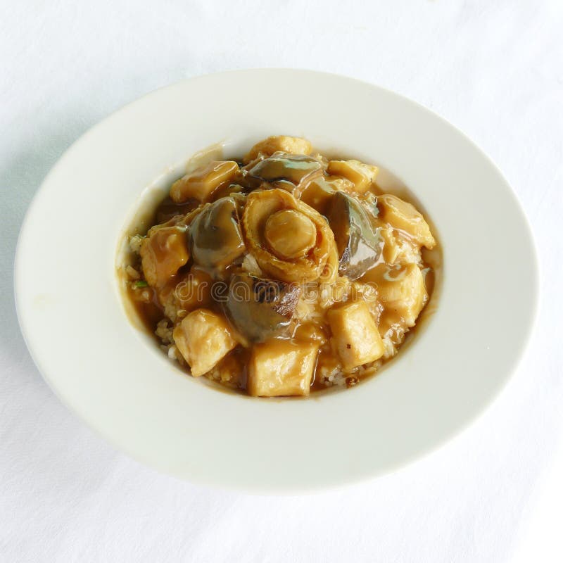 Arroz frito com ovo, coberto com abalone inteiro imagem de stock royalty free