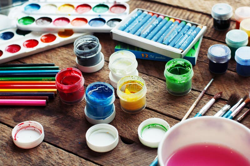 Art of Painting. Paint buckets on wood background. Different paint colors painting on wooden background. Painting set: brushes, paints, crayons, chalk, watercolor, acrylic paint on a wooden background