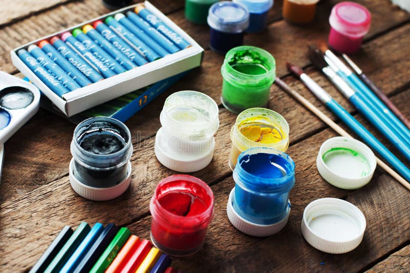 Art of Painting. Paint buckets on wood background. Different paint colors painting on wooden background. Painting set: brushes, paints, crayons, chalk, watercolor, acrylic paint on a wooden background